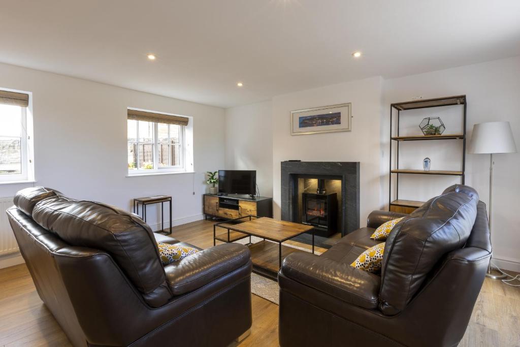 uma sala de estar com dois sofás de couro e uma lareira em Stable Cottage em Whitby