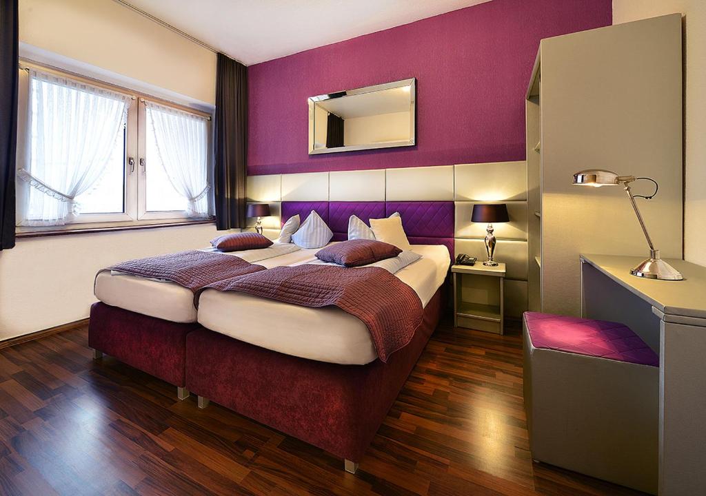 デュッセルドルフにあるホテル アム ヴィアハーンの紫の壁のベッドルーム1室(大型ベッド1台付)