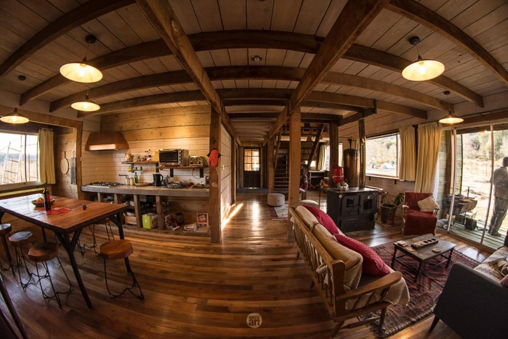 a living room with a wooden ceiling and a table at Hostal Dos Volcanes in Malalcahuello