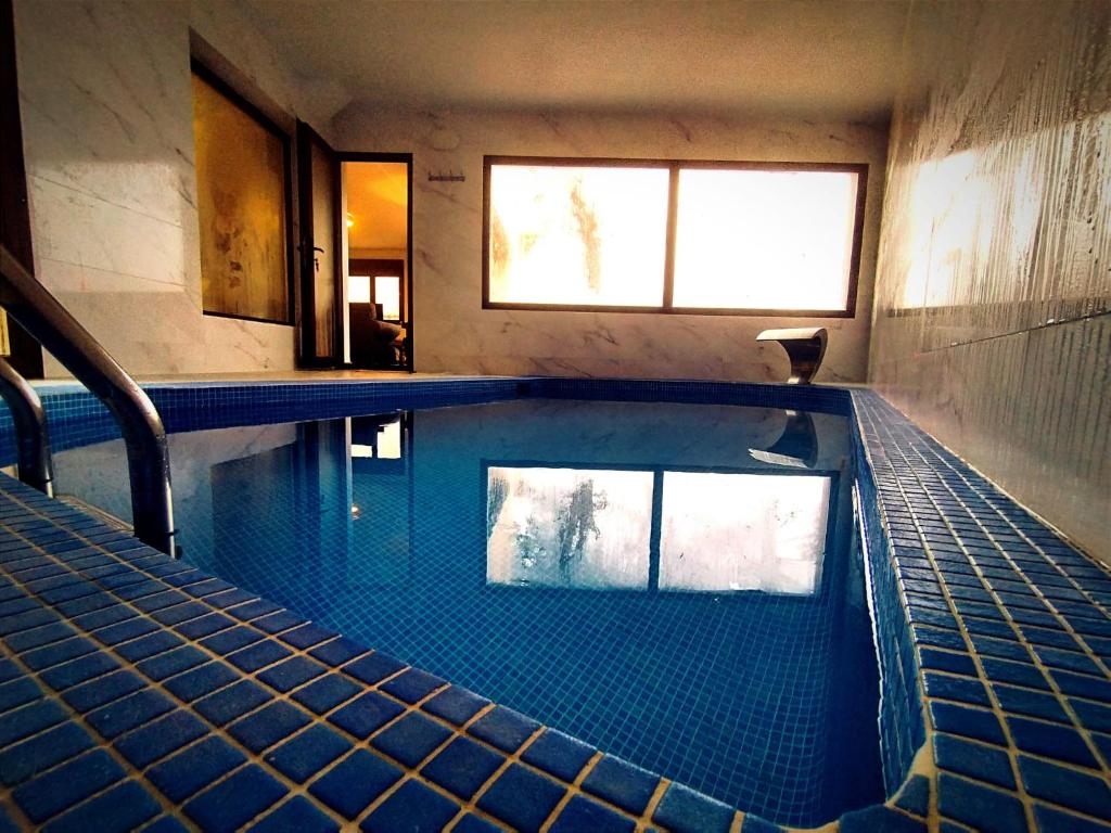 uma grande piscina com azulejos azuis num edifício em El Aprisco, con piscina climatizada en Hueva-Guadalajara em Hueva