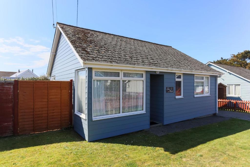 a small blue house with a fence in a yard at CROYDE SEA BREEZE 3 Bedrooms in Croyde