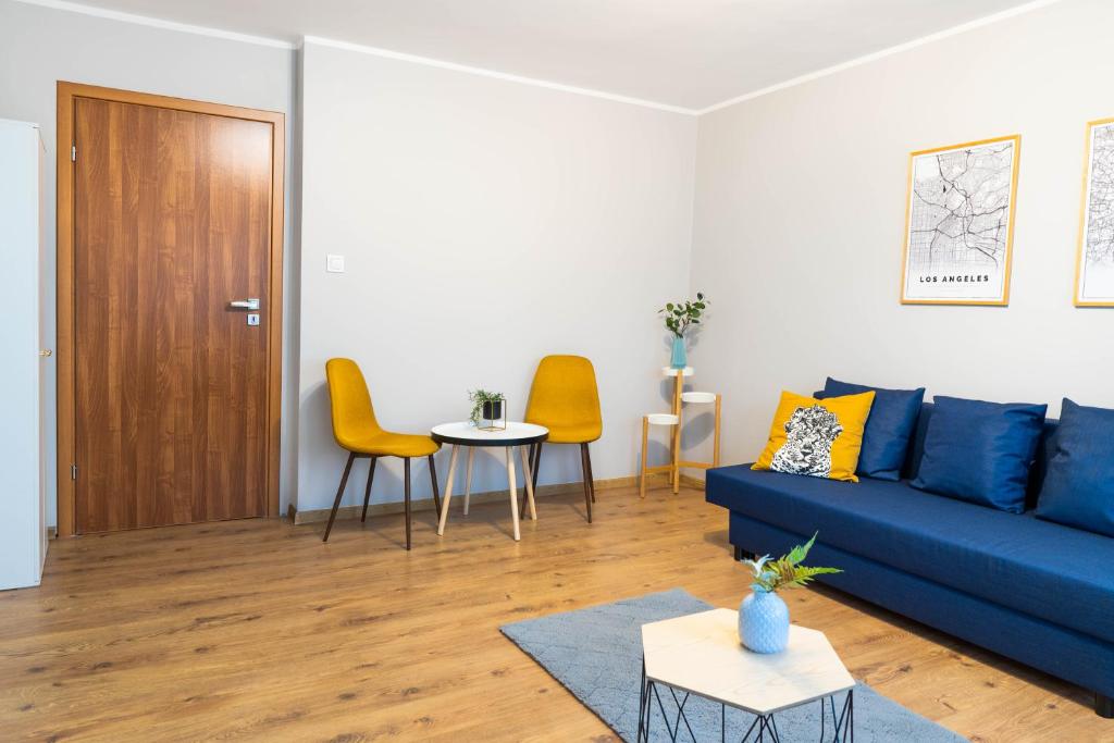 a living room with a blue couch and yellow chairs at Novinea Noclegi Ostrów Tumski in Poznań