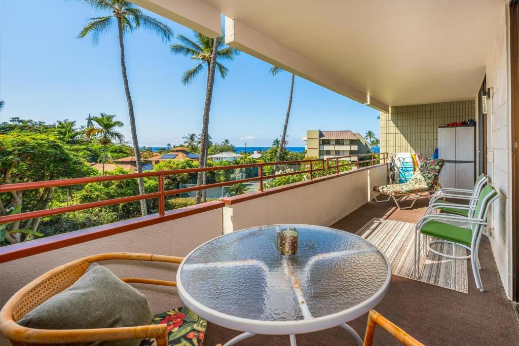 d'un balcon avec une table, des chaises et des palmiers. dans l'établissement Big Island White Sands Village by Coldwell Banker Island Vacations, à Kailua-Kona