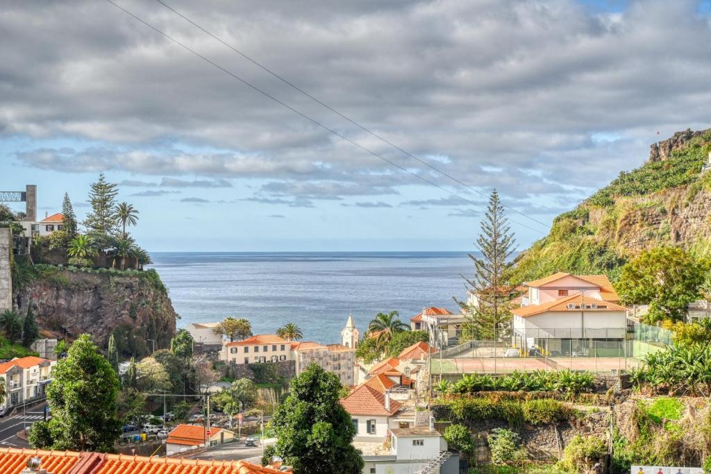 a town on a hill with the ocean in the background at Lidia's Place, a Home in Madeira in Ponta do Sol