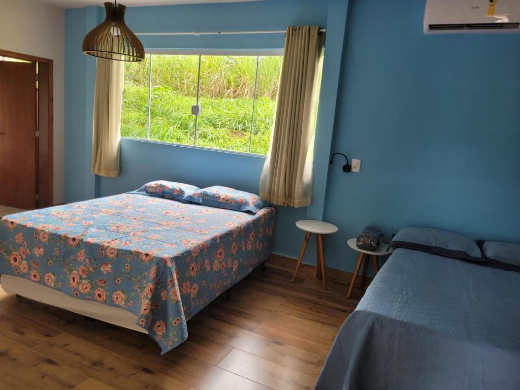 um quarto azul com uma cama e uma janela em POUSADA Chacara ENTRE NÓS em Holambra