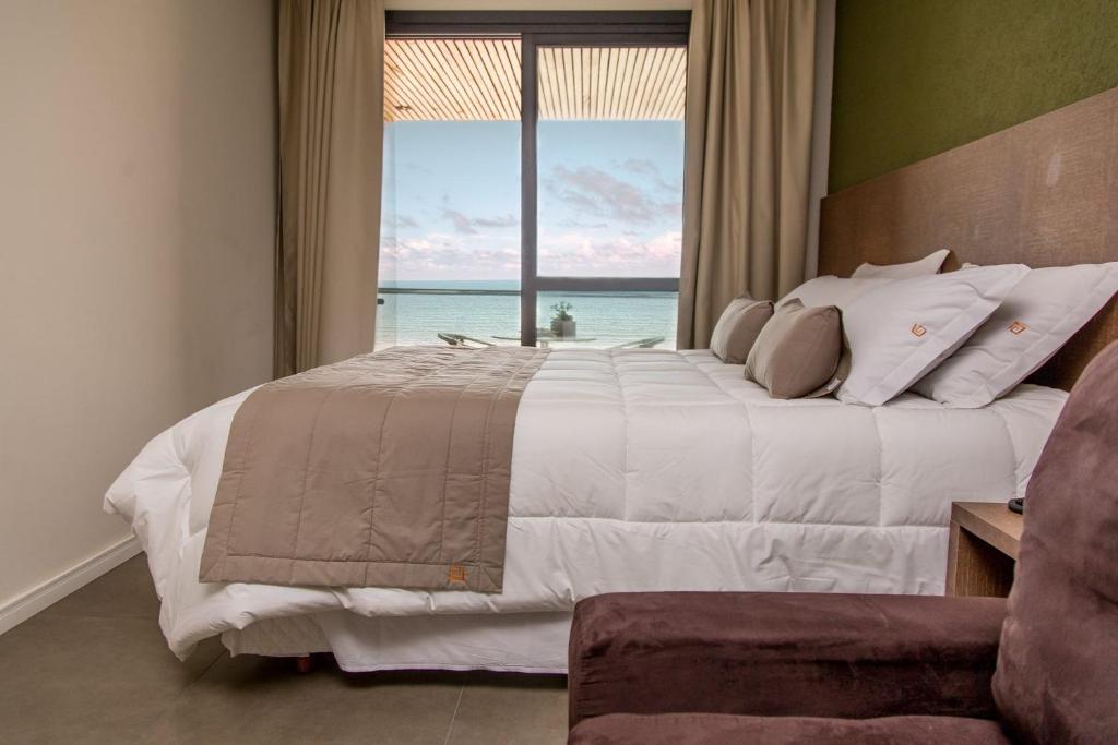a bedroom with a large bed with a view of the ocean at Aruá Pousada Boutique in Torres
