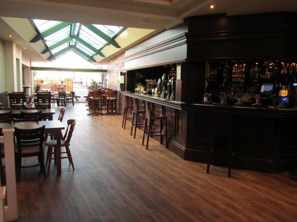a bar in a restaurant with tables and chairs at The Harboro Hotel in Melton Mowbray