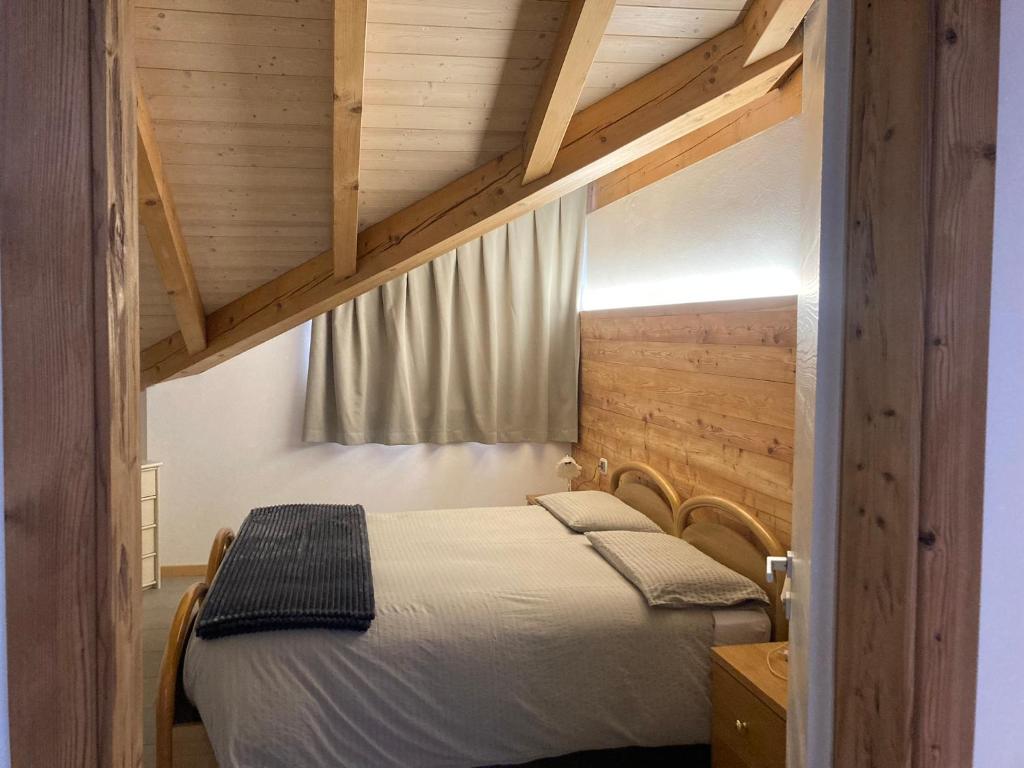 - une chambre avec un lit dans une pièce dotée de plafonds en bois dans l'établissement Appartamento Eleonora, à Vermiglio