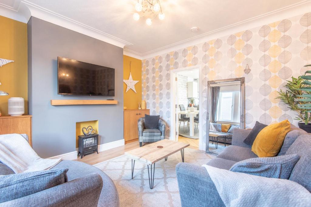 a living room with two blue couches and a tv at Bright, fresh, renovated 3 bedroom apartment in the heart of Montrose in Angus