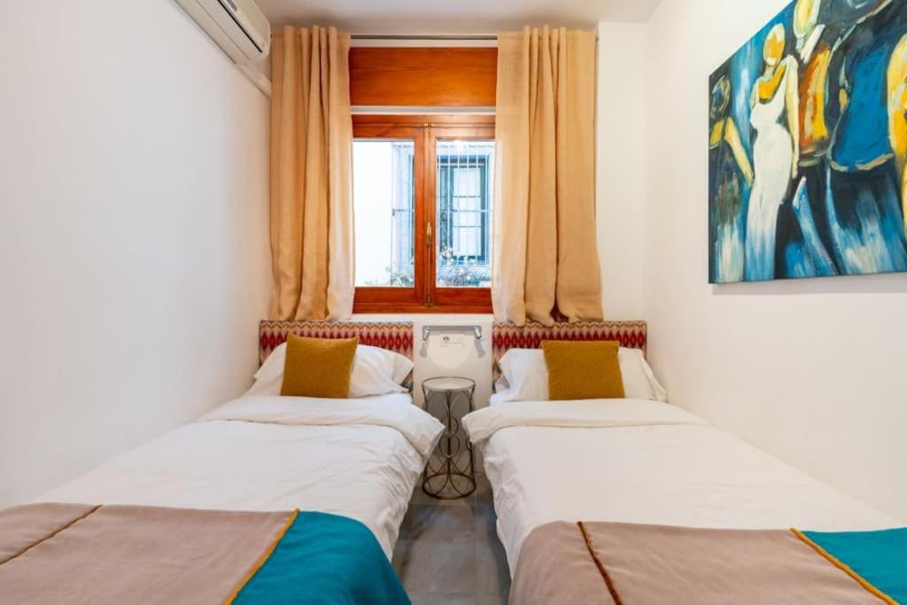 3 łóżka w pokoju z oknem w obiekcie AC Apartamento Familiar fantástica localizacion w Sewilli
