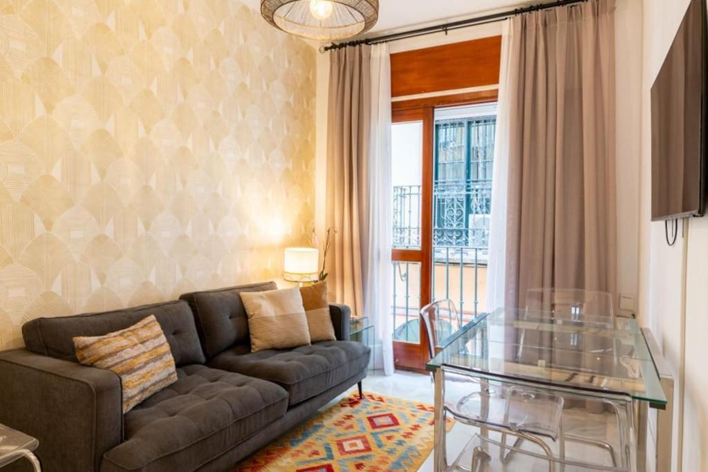 salon z kanapą i szklanym stołem w obiekcie AC Apartamento Familiar fantástica localizacion w Sewilli