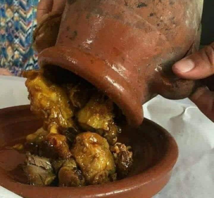 une personne plongeant un pot dans un plat de nourriture dans l'établissement Anacaccia, à Marrakech