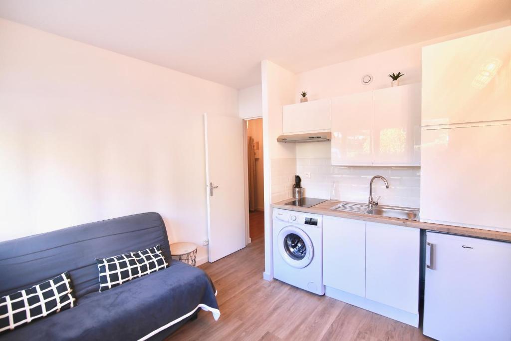 a kitchen with a couch and a washing machine at Les Hibiscus in Saint-Mandrier-sur-Mer