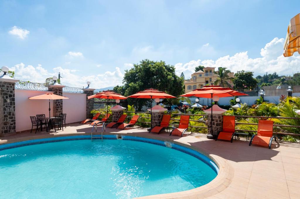 una piscina con sillas y sombrillas en Vivy Hill's Hotel en Puerto Príncipe