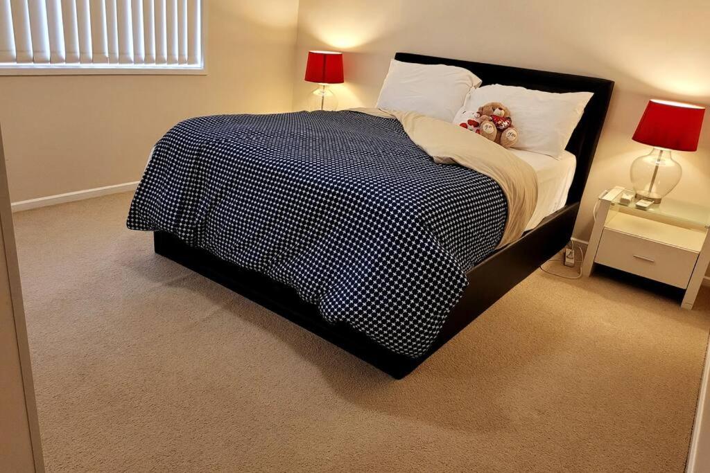 a bedroom with a black and white bed with two lamps at Cheerful 3 bedrooms with free parking in Kingswood