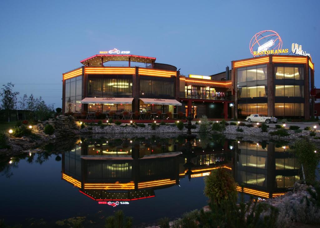 a building with a reflection in the water at night at Via Baltica in Sargėnai