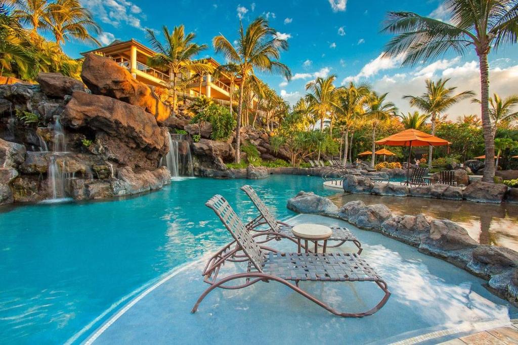 a pool at a resort with two chairs and a waterfall at Ho'olei Ocean View by Coldwell Banker Island Vacations in Wailea