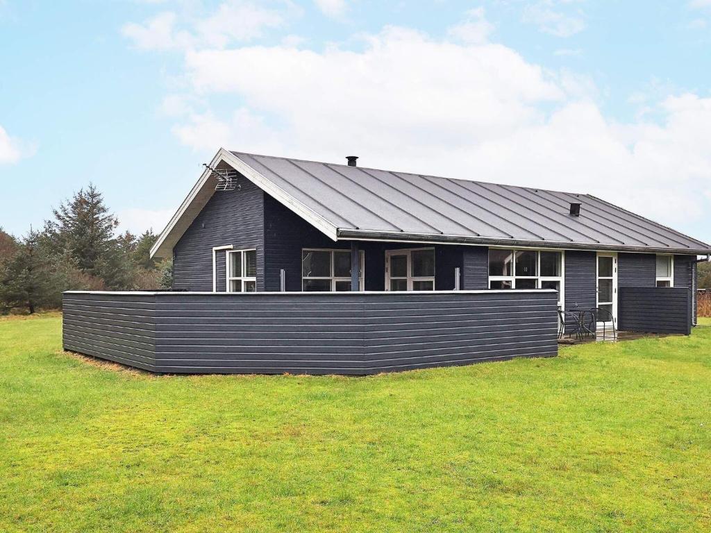 a black house sitting on top of a grass field at 6 person holiday home in L kken in Løkken