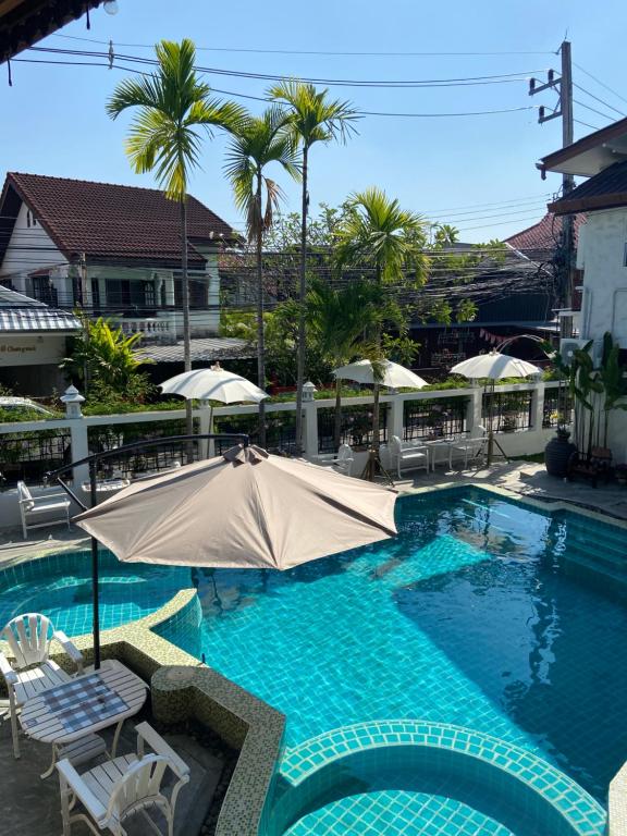 una piscina con ombrellone, sedie e palme di Mesa Garden Villa a Chiang Mai