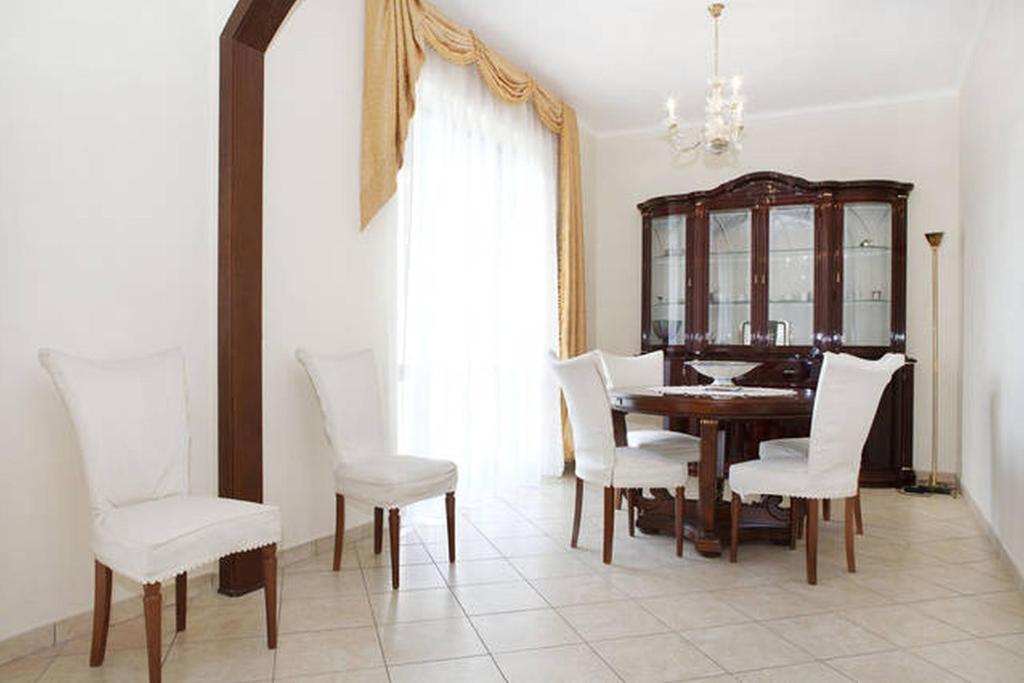 a dining room with a table and white chairs at Appartamento Vacanze Catania in Catania