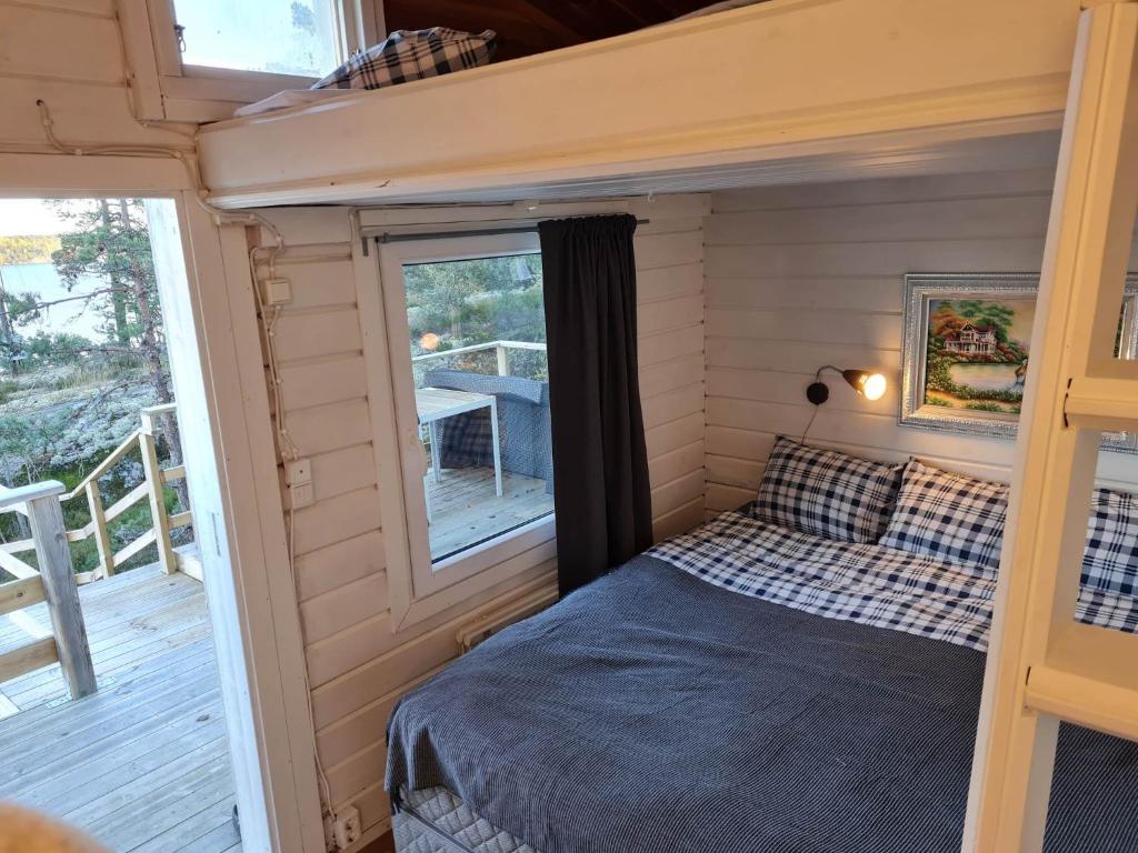 a bed in a tiny house with a porch at Archipelago villa, cabin & sauna jacuzzi with sea view, 30 minutes from Stockholm in Tyresö