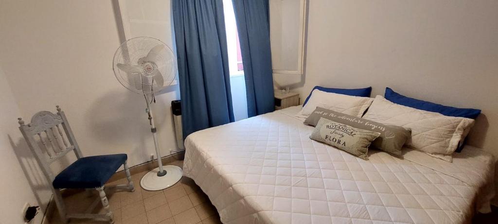 1 dormitorio con 1 cama blanca y ventilador en Depto. Céntrico en San Salvador de Jujuy