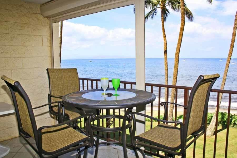 een tafel en stoelen op een balkon met uitzicht op de oceaan bij KIHEI BEACH, #303 condo in Kihei