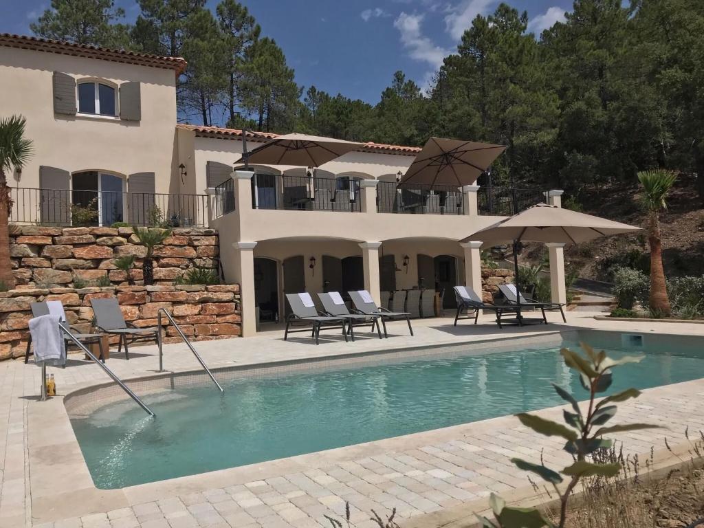 uma casa com piscina com cadeiras e guarda-sóis em Contemporary villa with swimming pool em Emponse