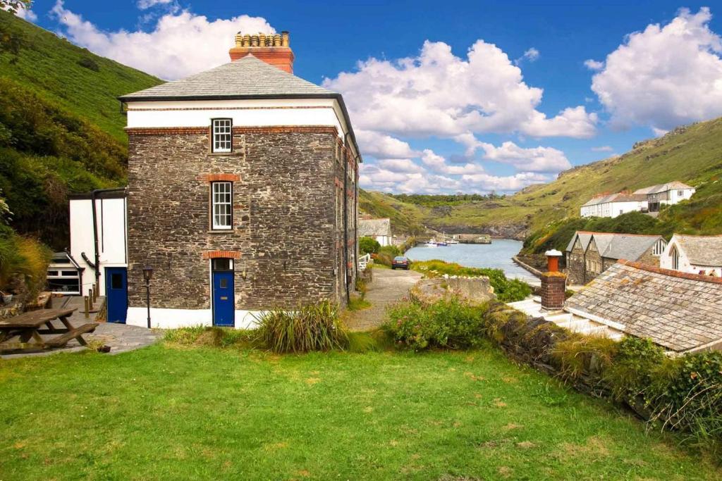 an old brick building with a river in the background at Bossy Castle in Boscastle