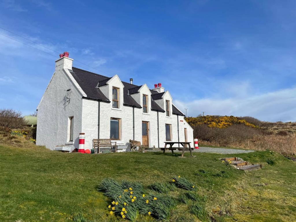 a large white house on top of a grass field at Red Chimneys Cottage in Husabost