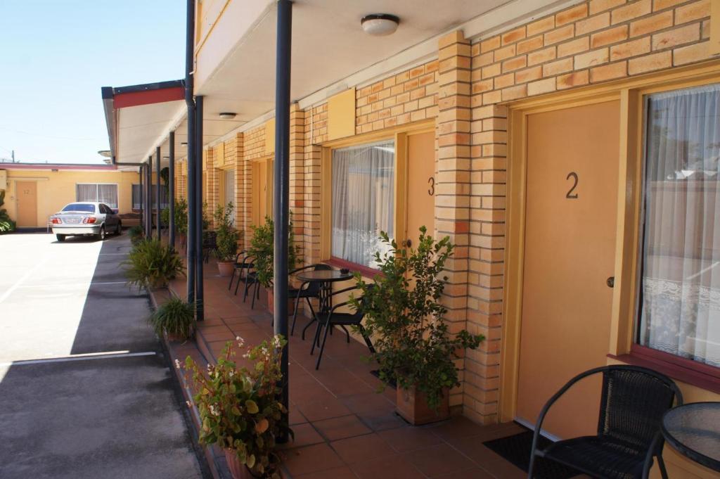 a patio with tables and chairs on a building at Ayrline Motel in Ayr