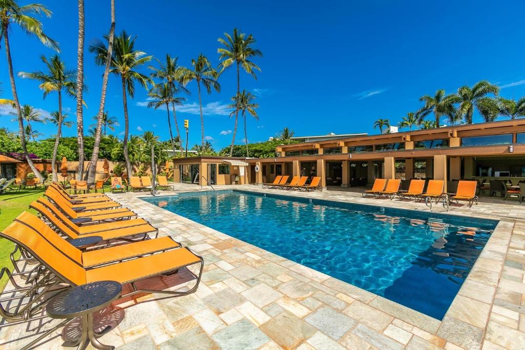 a resort swimming pool with lounge chairs and palm trees at Wailea Elua by Coldwell Banker Island Vacations in Wailea