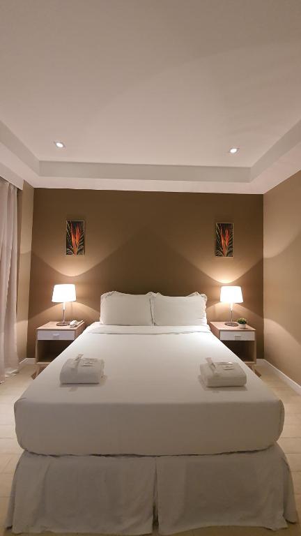 a bedroom with a large white bed with two lamps at Villa Verde Guest House in General Santos