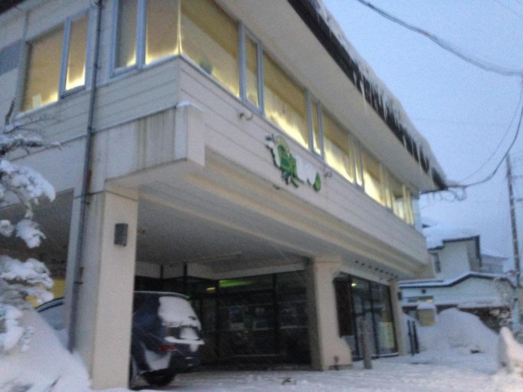un bâtiment avec une voiture garée à l'extérieur dans la neige dans l'établissement Matsupokkuri, à Zao Onsen