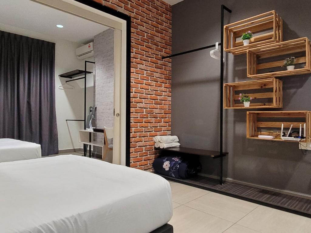 une chambre avec un lit blanc et un mur de briques dans l'établissement The Octagon Ipoh - Home Stay II, à Ipoh