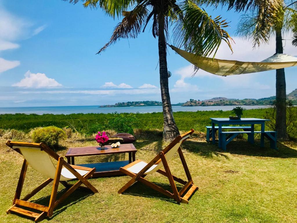 a hammock and a table and chairs on the beach at Corto Novo Maison d'hôtes-Camping in Nosy Be