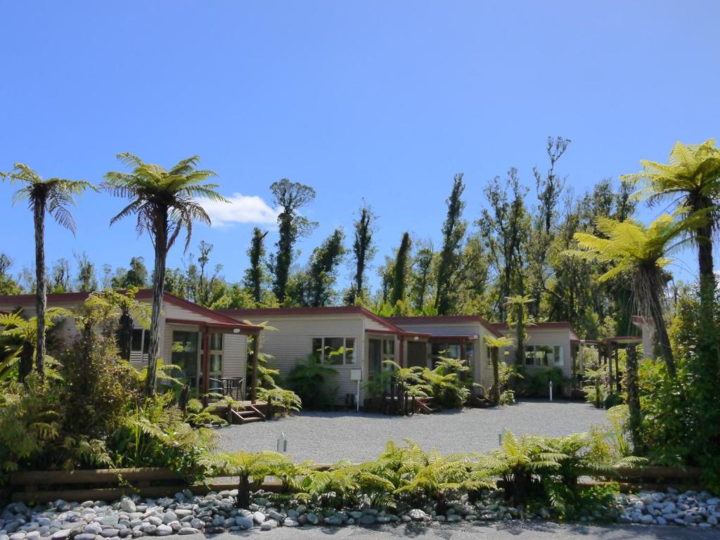 ein Haus mit Palmen davor in der Unterkunft 10 Cottages in Franz Josef