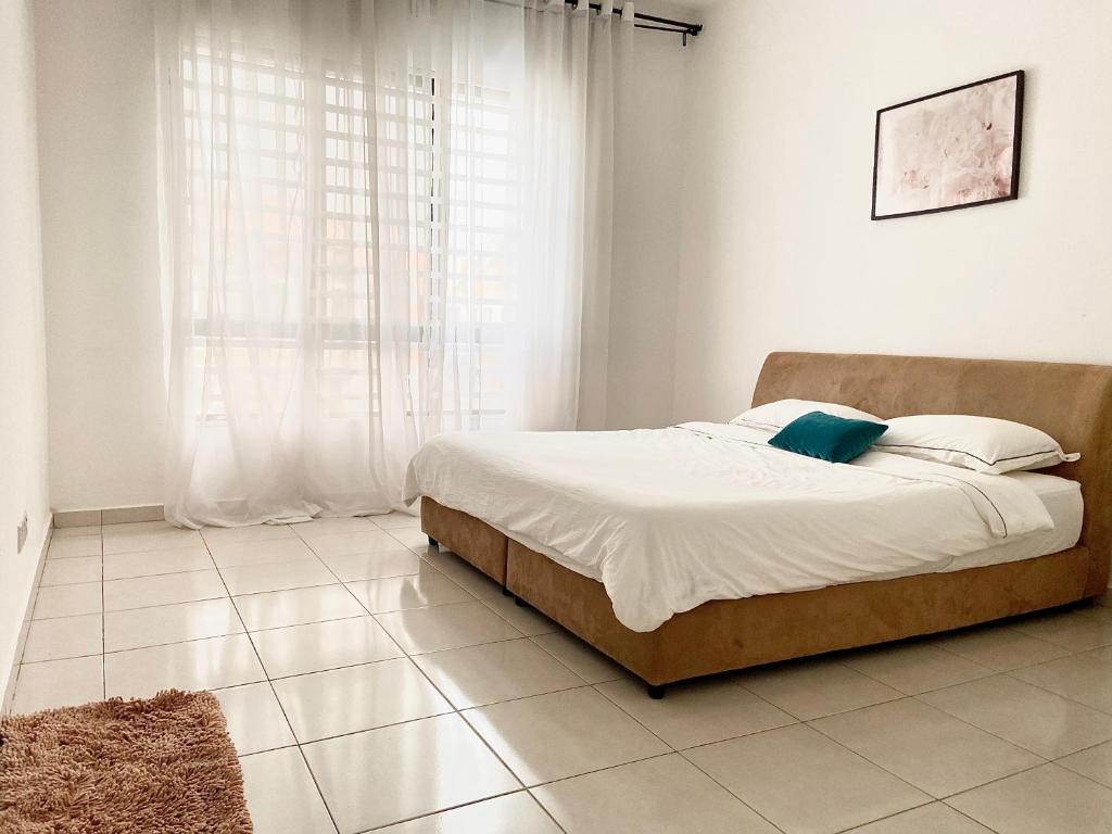 a bed in a white room with a large window at Melur Homestay in Setia Alam