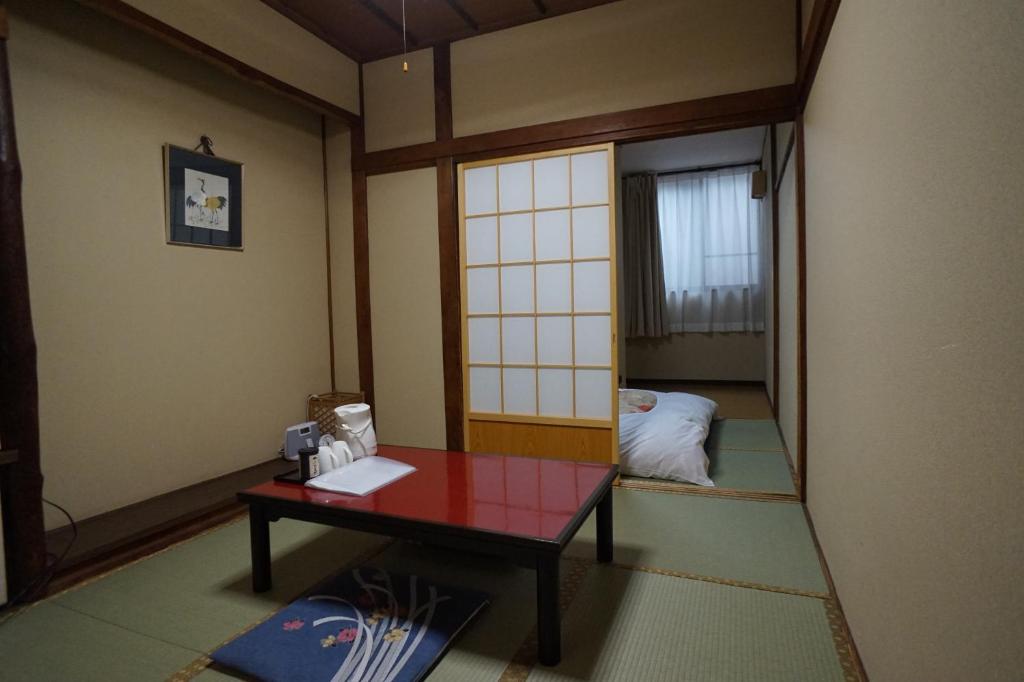 a room with a table and a room with a bed at Ryokan Katsutaro in Tokyo