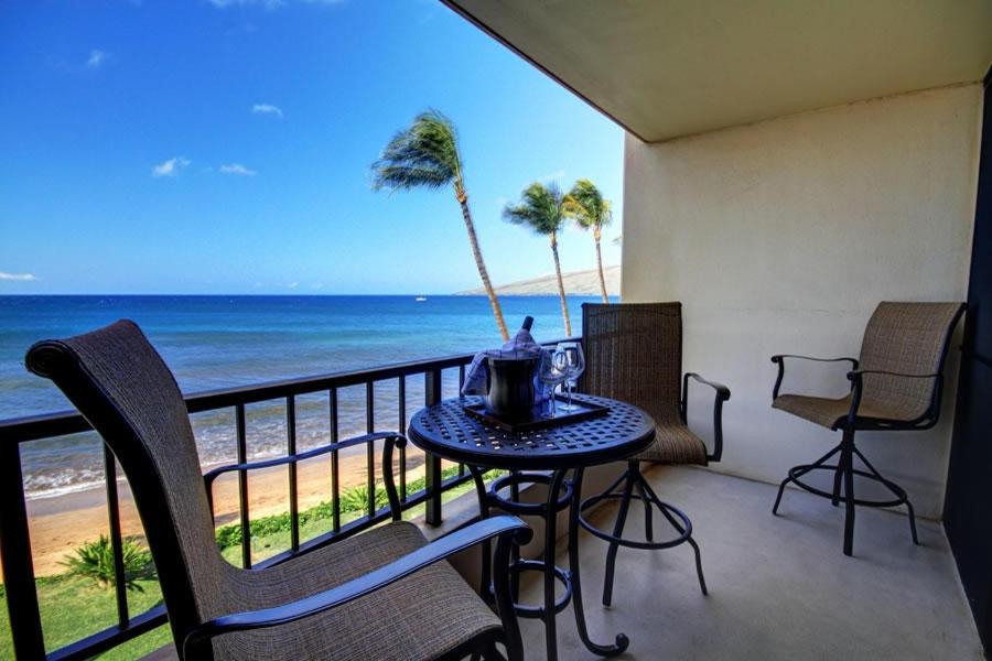 een balkon met een tafel en stoelen en de oceaan bij SUGAR BEACH RESORT, #329 condo in Kihei