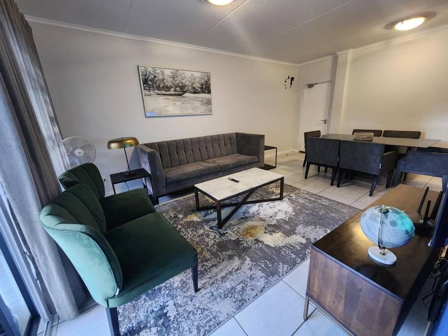 a living room with a couch and a table at Modern 3-bed Garden Apartment in Waterfall in Midrand