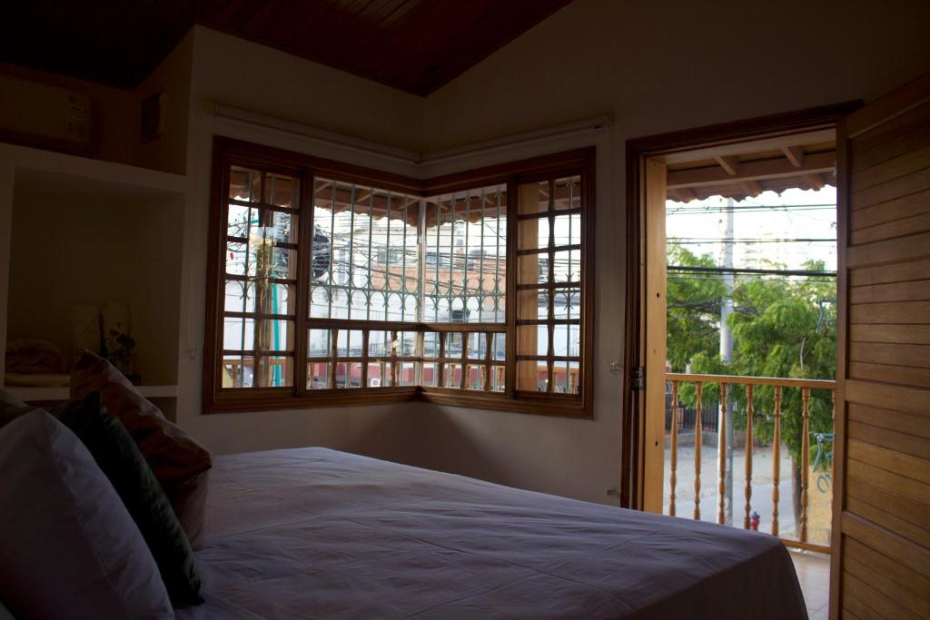 1 dormitorio con ventanas, 1 cama y balcón en Hostal Magdalena en Santa Marta