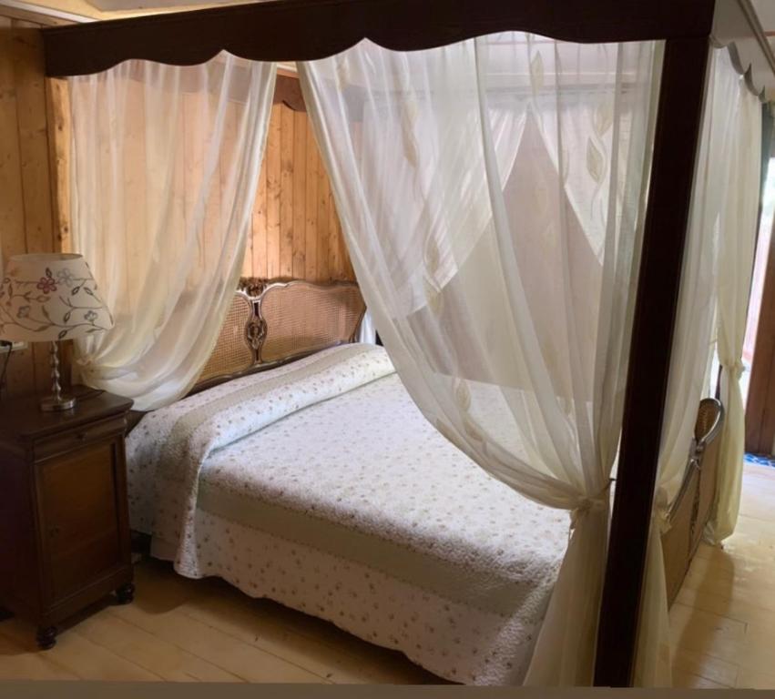 een slaapkamer met een hemelbed en witte gordijnen bij Casa Fogli Casa Vacance & Events in Campiglia Marittima