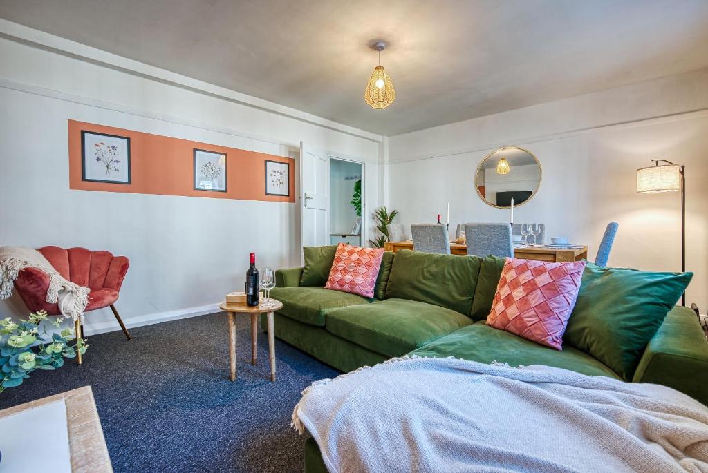 a living room with a green couch and a table at Brewery Loft - 3 Bedroom Bright Spacious apartment in the centre of town, Wifi, Netflix in Cirencester