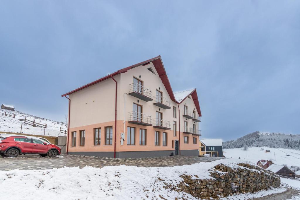 um edifício com um carro vermelho estacionado na neve em Шепіт Лісу em Bukovel