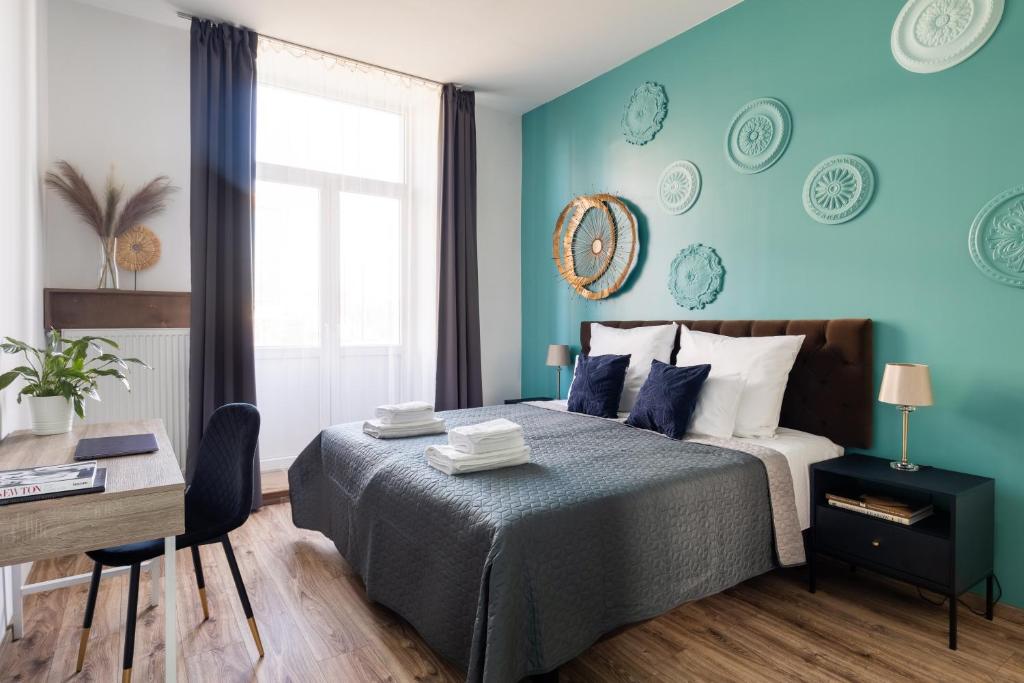 um quarto com paredes azuis e uma cama com uma secretária em Luxe Living Castle View em Cracóvia