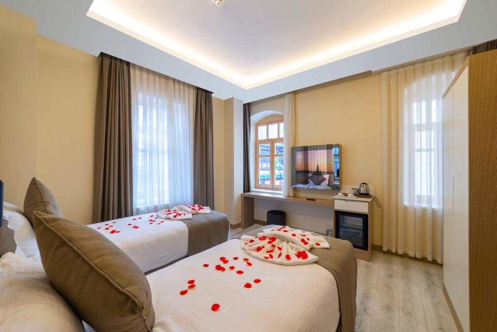 a hotel room with two beds with red roses on them at BRAKO HOTEL in Istanbul