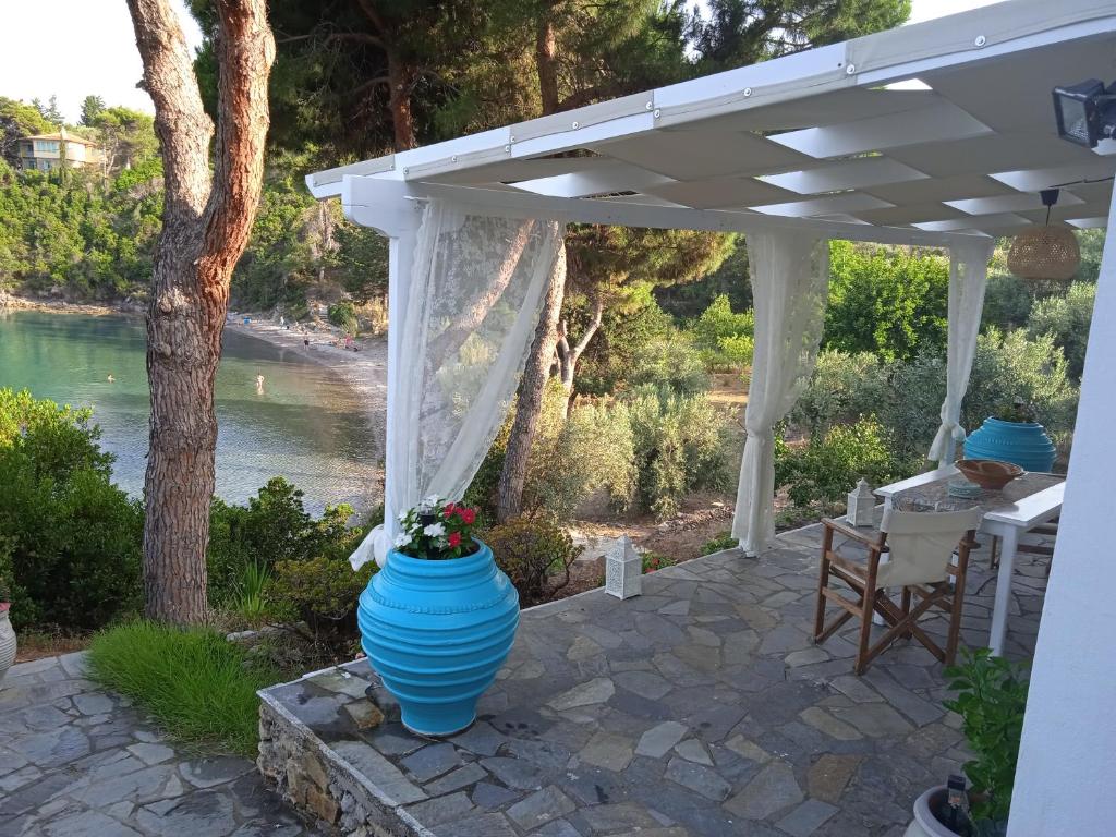 a patio with a white pergola and a blue vase at Marianna Studios in Aghios Petros Alonissos