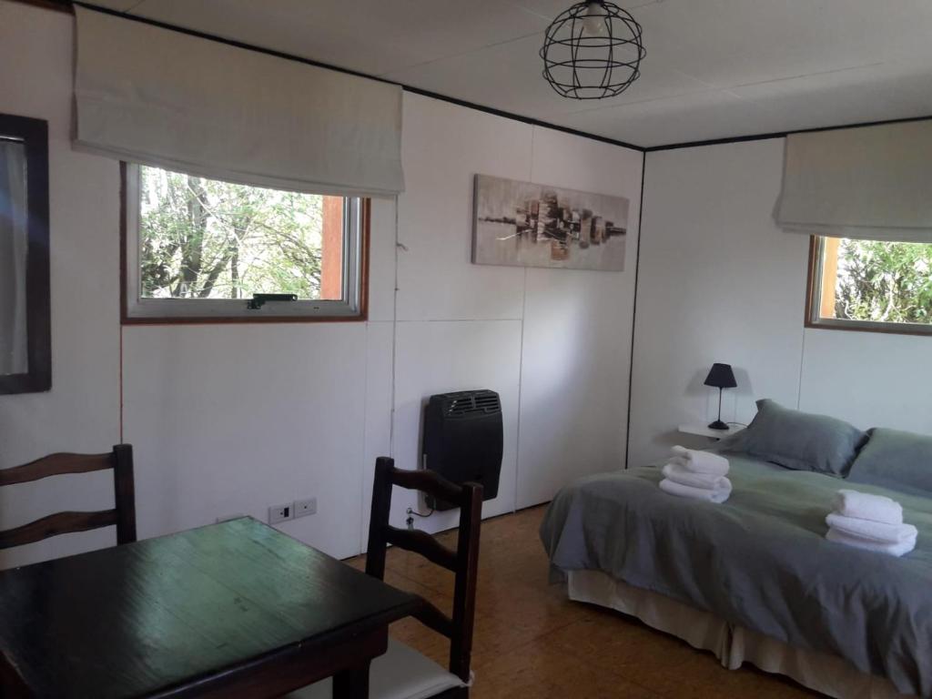 1 dormitorio con mesa, cama, mesa y sillas en vagones de la patagonia en El Calafate