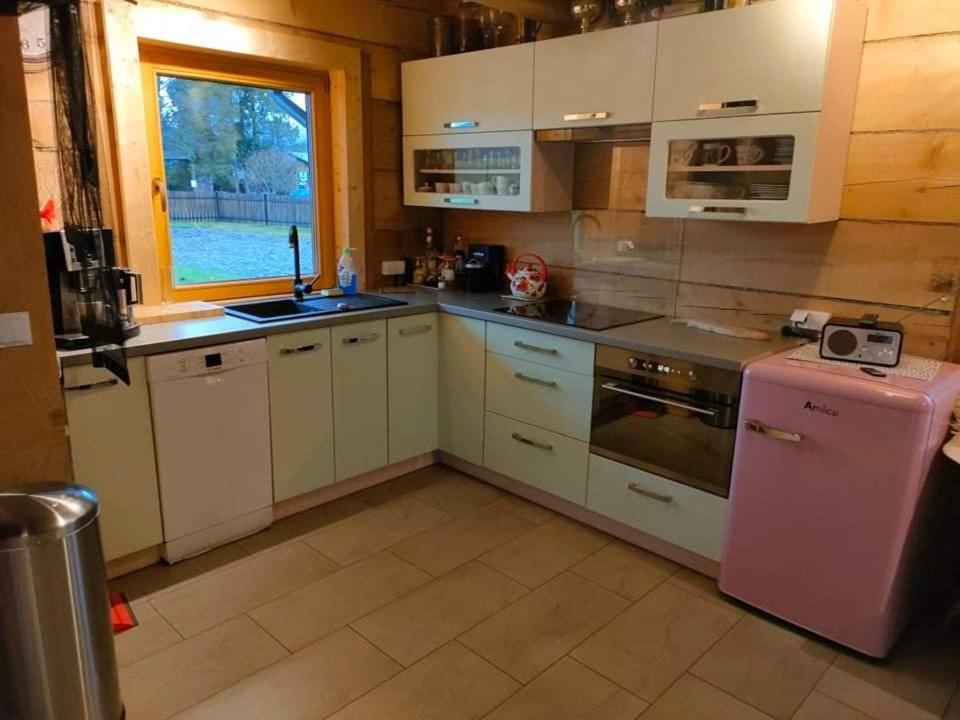 cocina con armarios blancos y nevera rosa en BIJAKÓWKA en Ustrzyki Dolne